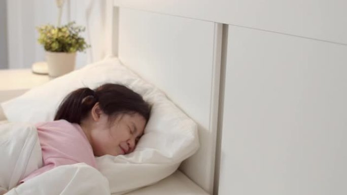年轻的亚洲女孩睡在家里。亚洲日本女小孩放松休息躺在床上睡觉，晚上在家卧室感到舒适和平静。慢动作镜头。