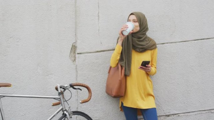戴着头巾的女人在街上喝咖啡带走咖啡