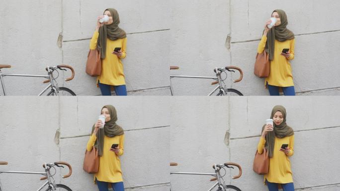 戴着头巾的女人在街上喝咖啡带走咖啡