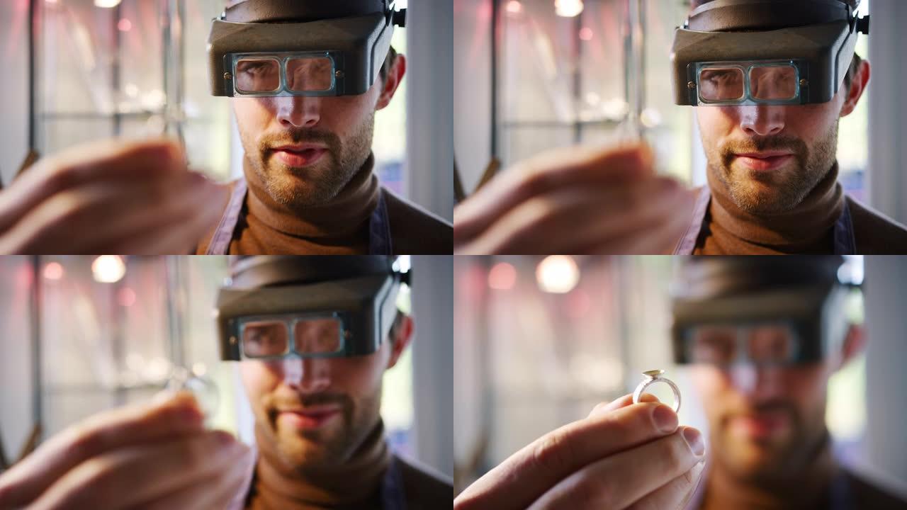 男性珠宝商看戒指通过头带放大镜在工作室的特写