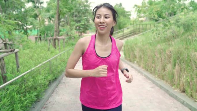 慢动作-健康美丽的年轻亚洲跑步女子穿着运动服在城市公园的街道上跑步和慢跑。生活方式适合和积极的女性在
