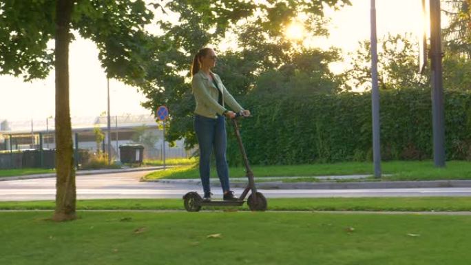 慢动作: 年轻女子在现代城市的人行道上骑着电动踏板车