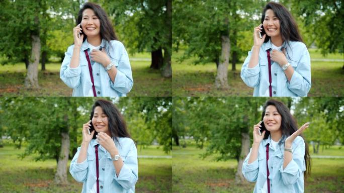 快乐亚洲女士在手机上聊天的慢动作笑在外面