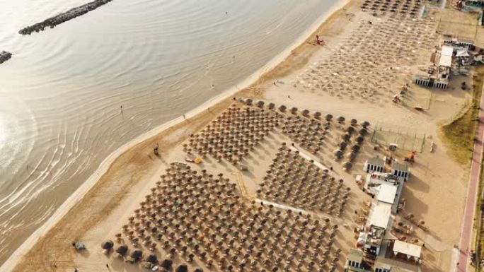 无人机飞越史诗般的夏季意大利海岸，公共沙滩上有成排的椅子。旅游和旅游概念。
