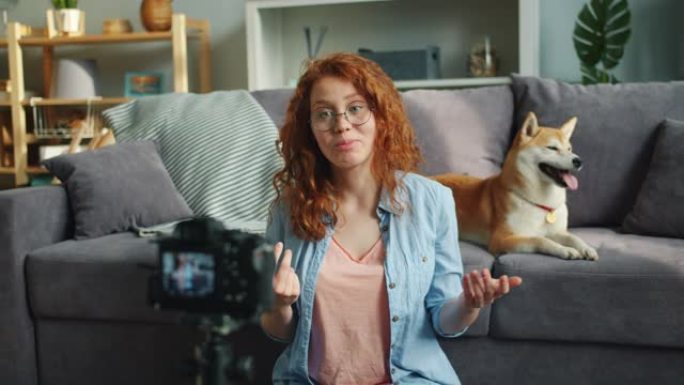 幸福的女人用专业相机在家录制关于狗的视频