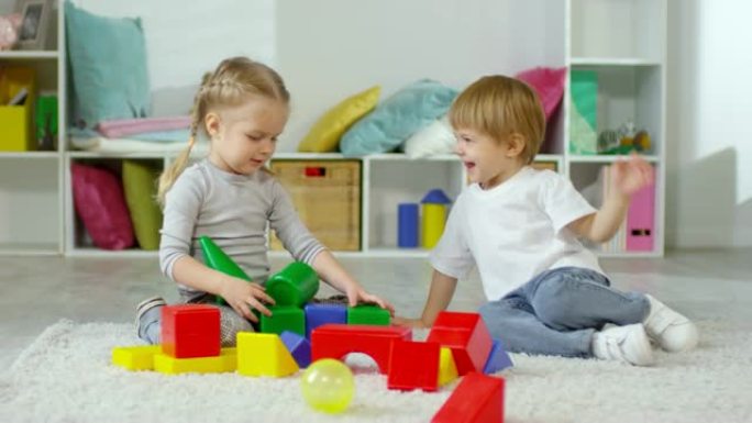 快乐的小男孩和女孩在地板上玩玩具积木塔