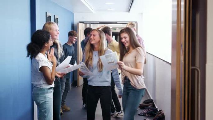 兴奋的青少年高中生在学校走廊庆祝考试成绩