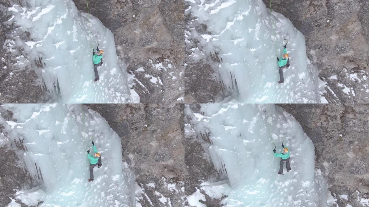 空中: 女人在爬上冰冷的瀑布时小心地放置冰镐