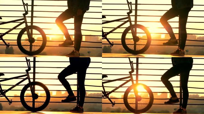 男子站在日落背景上，骑着自行车，特写镜头。