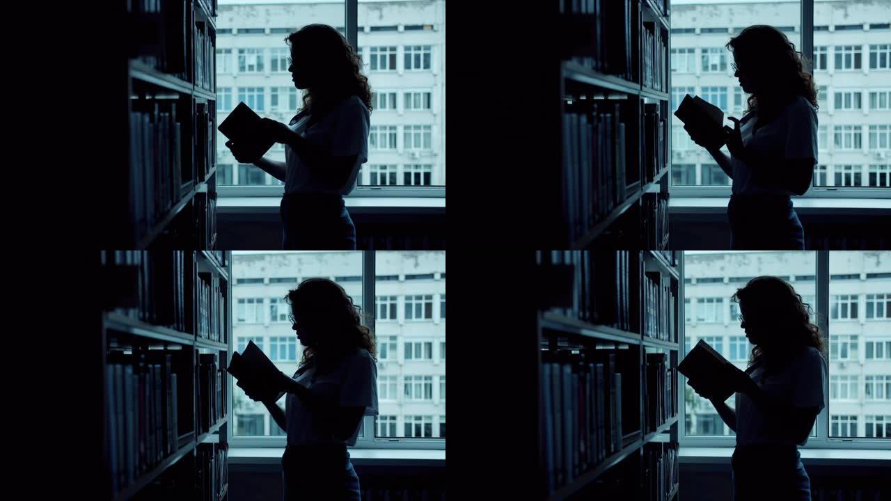 手握在图书馆阅读中选择书籍的聪明女人的剪影