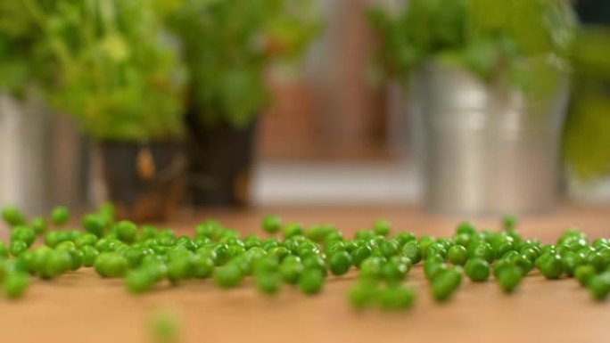 宏观，dop: 美味的绿豌豆在木制厨房柜台上滚动并弹跳。