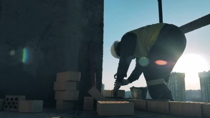 建造者正在铺设砖块并将其固定在多层建筑物中。建筑工地的建筑工人。