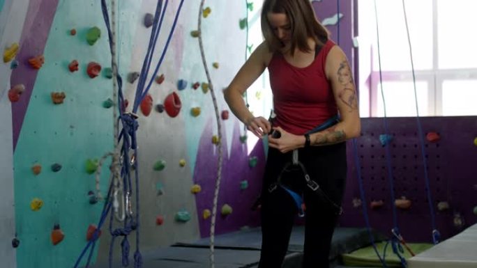 高加索女性登山者在攀岩健身房穿上安全装备