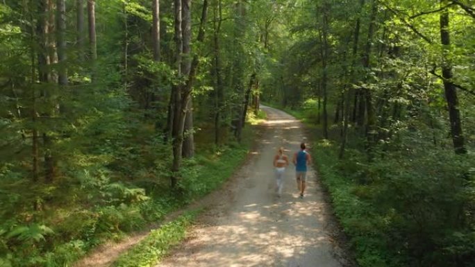无人机: 运动情侣在树林中慢跑。