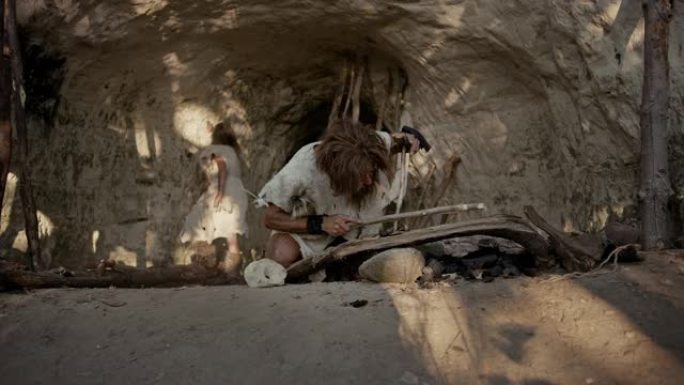 原始穴居人穿着动物皮试图用弓钻方法生火。尼安德特人点燃了人类文明史上的第一把人造火。生火做饭。放大镜