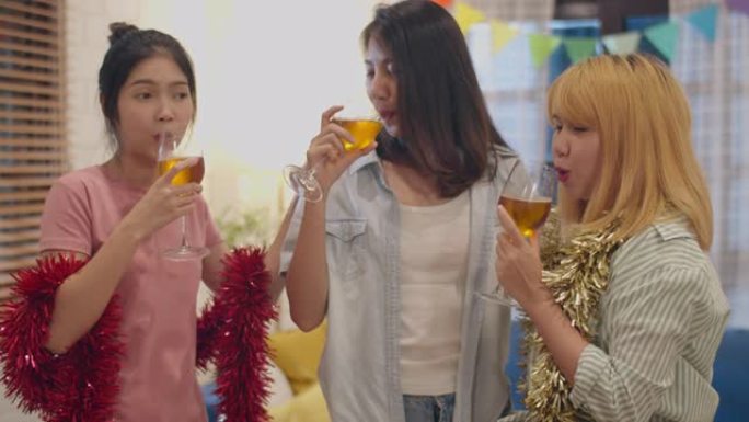 一群亚洲女性在家里聚会，女性在晚上的客厅里喝鸡尾酒跳舞和唱歌。青少年年轻朋友玩游戏，庆祝节日概念。慢