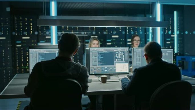 在数据中心控制室的台式计算机上工作的IT编程人员团队。年轻的专业人士编写复杂的编程代码语言