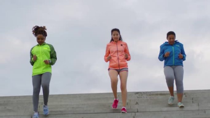 从桥上下来的三名多种族女跑步者