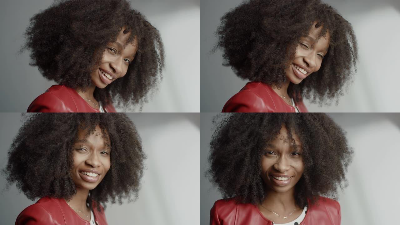 迷人的黑人女孩，郁郁葱葱的卷发摆姿势拍摄时尚杂志照片。美丽的女孩调皮地微笑，表演和玩面部表情。在专业