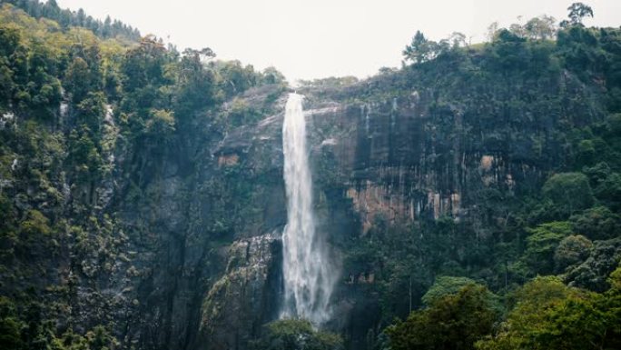 美丽的中等镜头，大型丛林瀑布的景观背景在异国情调的原始斯里兰卡森林中冲下。