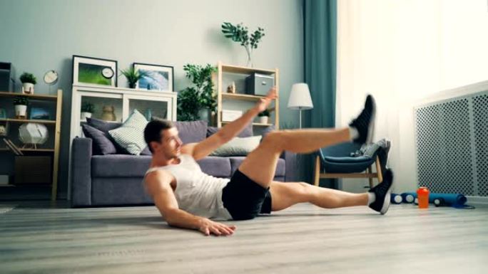 活跃的家伙在家锻炼，躺在地板上做运动，抬起腿和手臂