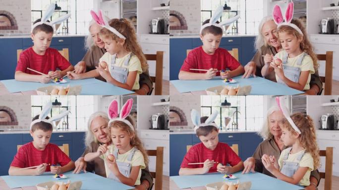 祖母带着孙子戴着兔子耳朵在家里一起装饰复活节彩蛋