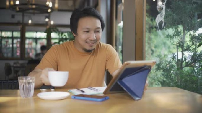 致力于平板电脑和喝咖啡的亚洲男子