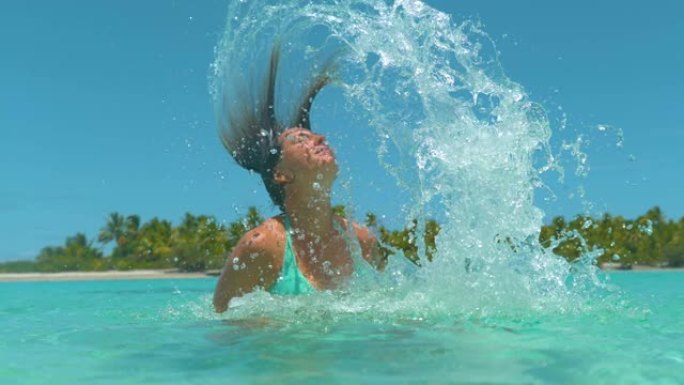 慢动作: 度假的女人将湿头发向后鞭打并喷洒玻璃水
