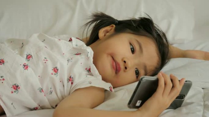 亚洲小女孩正在看电话。孩子正在玩智能手机。