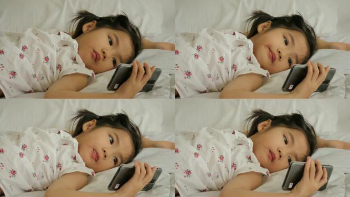 亚洲小女孩正在看电话。孩子正在玩智能手机。