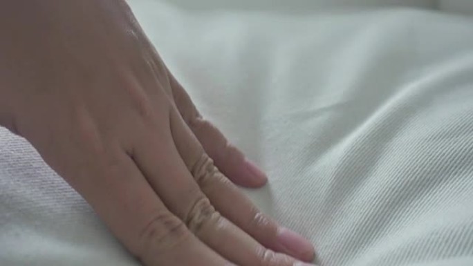 女人的手抚摸着非常柔软干净的床单。