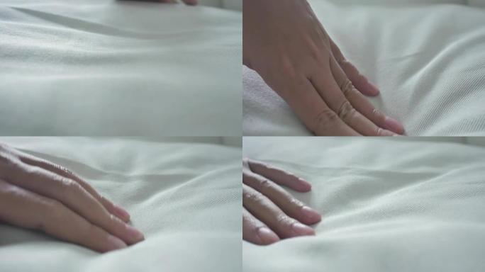女人的手抚摸着非常柔软干净的床单。