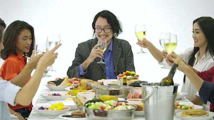 一群亚洲人一起在餐桌上敬酒，并在新年晚会上用美味的饭菜庆祝圣诞节。有节日和庆祝概念的人。