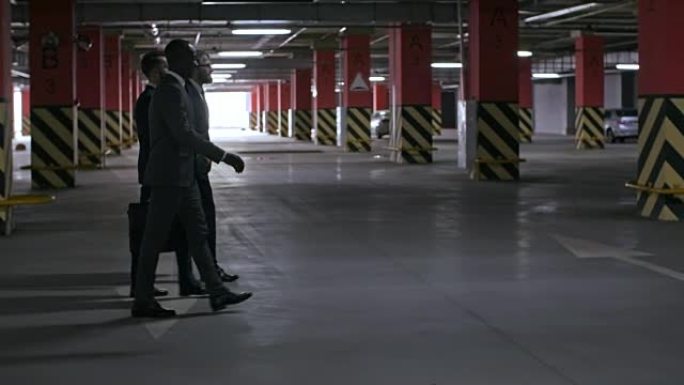 穿西装的男人在地下停车场散步