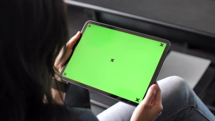年轻女子在沙发上使用绿色屏幕的数字平板电脑，水平