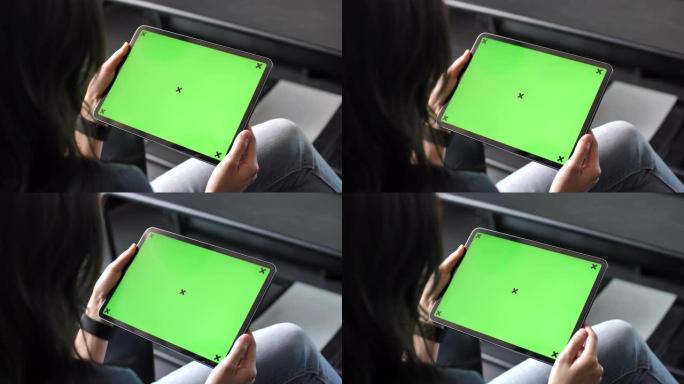 年轻女子在沙发上使用绿色屏幕的数字平板电脑，水平