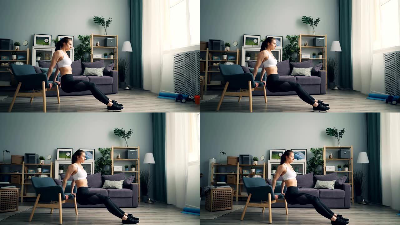漂亮女孩独自在公寓里用扶手椅训练在家做俯卧撑