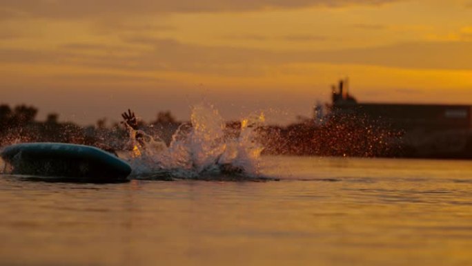 超级SLO MO Man在日落时从冲浪板上摔下来