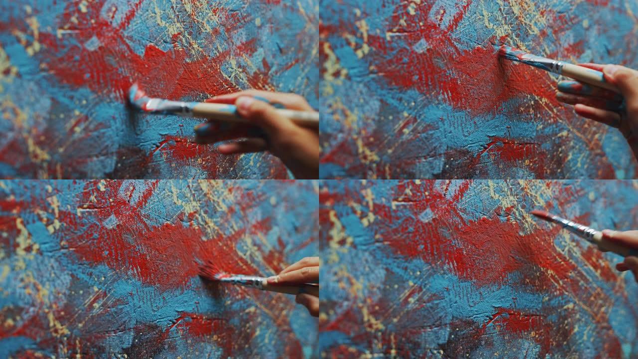 女艺术家手的特写镜头，拿着画笔，用红色颜料画画。色彩缤纷，富有情感的油画。当代画家创作现代抽象美术作