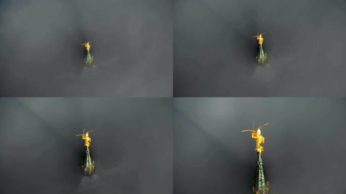 史诗般的空中特写镜头，在深灰色云层上方的圣米歇尔城堡尖顶上拍摄了天堂般的金色雕像。