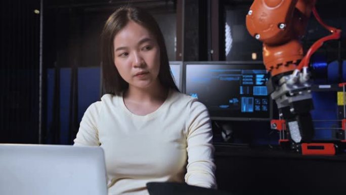 一个未来主义的假肢机器人手臂由一名亚洲少女发展工程师在研究实验室晚工作。手臂移动手指。技术，工作到很