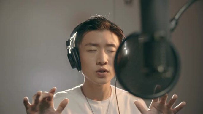 年轻的亚洲歌手在录音室唱歌