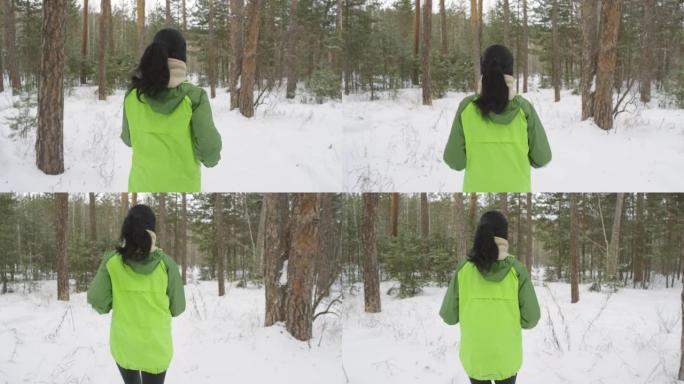 冬天在森林里慢跑的女人的后视图