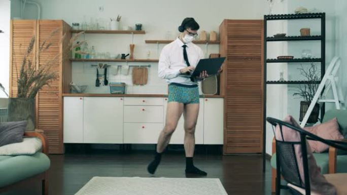 没有裤子的商人正带着笔记本电脑沿着厨房走