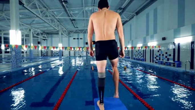 残疾游泳者在游泳池附近热身，腿部假肢。