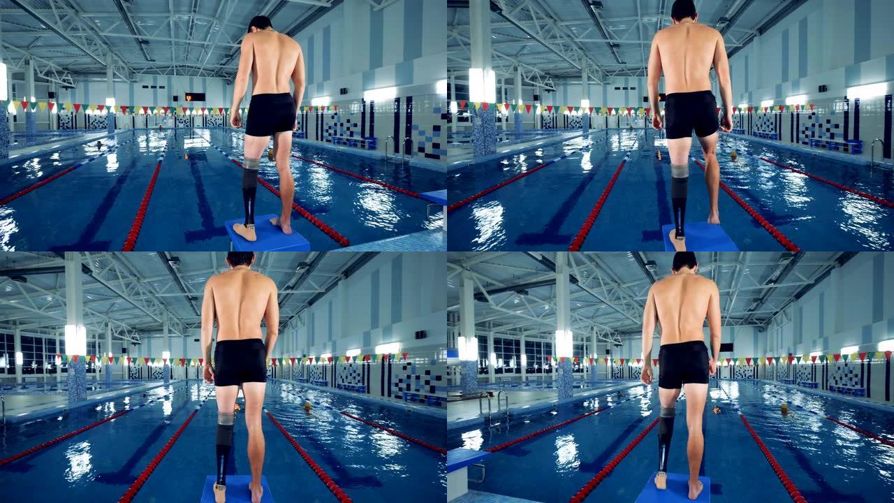 残疾游泳者在游泳池附近热身，腿部假肢。