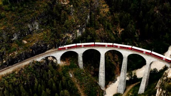 在史诗般的夏季瑞士阿尔卑斯山著名的历史悠久的Landwasser高架桥上，无人驾驶飞机飞越冰川快车。