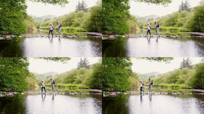 年轻夫妇在英国湖区徒步旅行时使用垫脚石过河的慢动作镜头