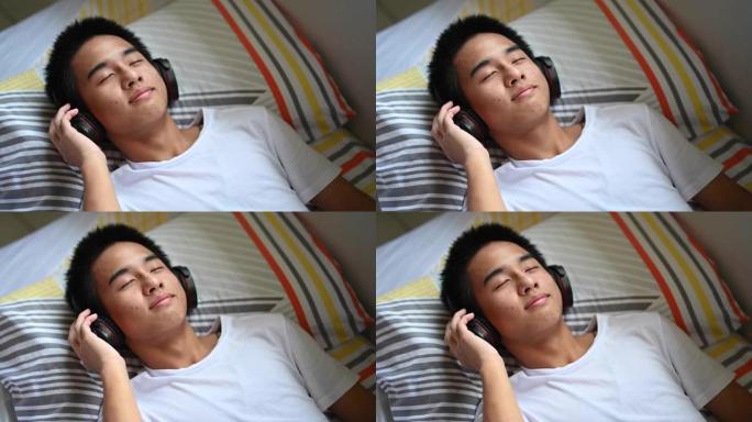 周末躺在床上的一个亚洲华裔少年男孩在家用耳机听音乐