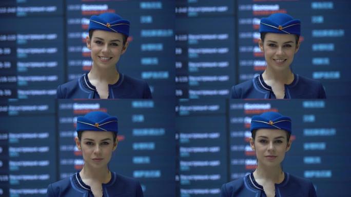 美丽的空姐穿着制服，对着镜头微笑站在飞行状态屏幕前